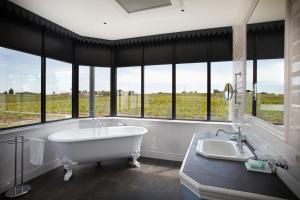 a large bathroom with a tub and a sink and windows at Château la Rose Perriere in Lussac +30 photos