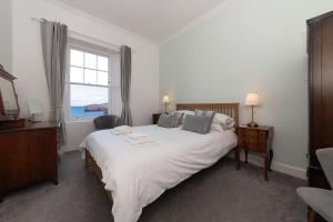 a bedroom with a large white bed with a window at Beresford Cottage in North Berwick