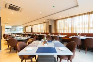 a dining room with tables and chairs and windows at Grand Continent Hotel, Rameswaram in Rāmeswaram