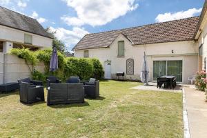 a yard with chairs and umbrellas and a house at Le Gîte Des Anges - 4pers, Piscine in Angé