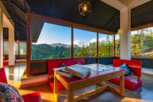 a room with a table and chairs and large windows at Monkey Tribe Vagamon in Vagamon