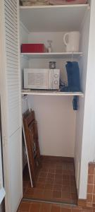 a closet with a shelf with a microwave and other items at Bouquin-couette in Plouguerneau