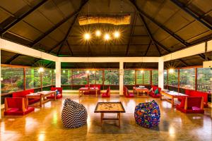 a large room with red chairs and tables and windows at Monkey Tribe Vagamon in Vagamon