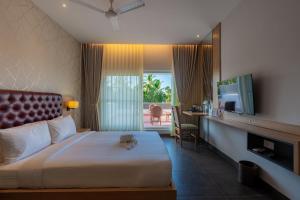 a hotel room with a bed and a television and a balcony at Grand Continent Hotel, Rameswaram in Rāmeswaram