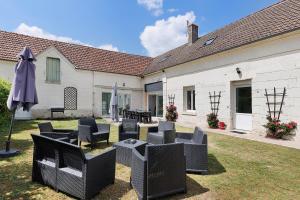 a patio with chairs and an umbrella in a yard at Le Gîte des Anges - 12pers, Piscine in Angé