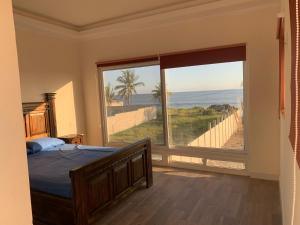 a bedroom with a bed and a large window at Villa Patty by the beach in El Conacaste