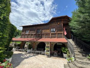 a large wooden house with tables and chairs in front of it at BAR RESTORANT HOTEL ALPET Elbasan in Elbasan