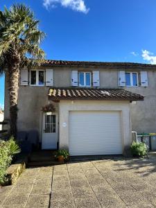 ein Haus mit einem Garagentor und einer Palme in der Unterkunft Villa Marguerite in Castelnau-Rivière-Basse