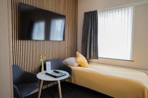 a hotel room with a bed and a chair and a window at Hotel Oepkes in West-Terschelling