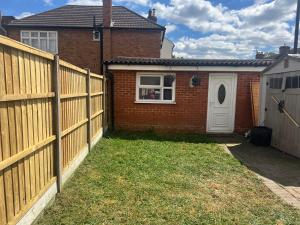 a fence in front of a house with a white door at Compact single room A near Heathrow with 24 hour buses to all terminals in Feltham
