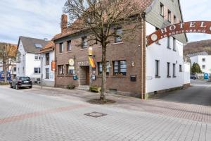 a building on a street with a tree in front of it at Gasthaus, Hotel am Dreienberg in Friedewald