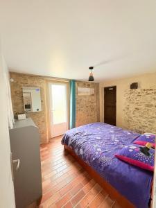 a bedroom with a purple bed in a room at Charmant gite en pierre in Gratot