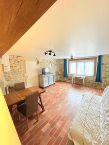 a living room with a wooden floor and a bedroom at Charmant gite en pierre in Gratot