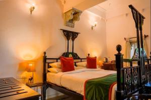 a bedroom with a large bed with red pillows at Amet Haveli - A Heritage Hotel Udaipur in Udaipur +69 photos