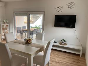a dining room with a white table and a television at Lorenzo apartment in Milna
