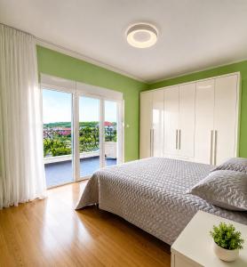 a bedroom with a large bed and a large window at Krimovica Sunset Spacious Apartment with Sea View and Pool in Krimovice
