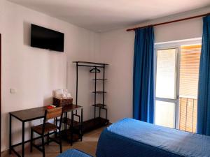 a bedroom with a desk and a bed and a window at Hostal Fantoni in Cádiz