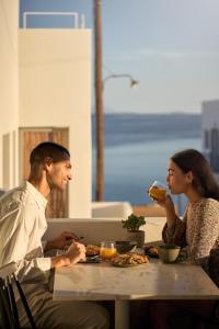a man and a woman sitting at a table with food at Paros Cape Suites in Naousa