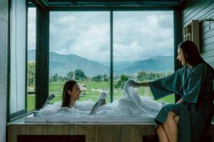 a woman sitting in a bath tub with a window at Sangthong Resort at Chiang Klang in Chiang Klang