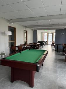 a pool table in a room with tables and chairs at Hotell Vänersborg in Vänersborg
