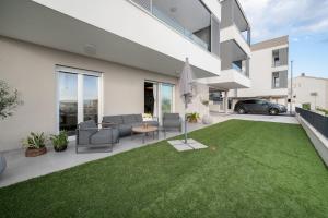 a backyard with a lawn in front of a building at Lejla Garden Apartment in Podstrana