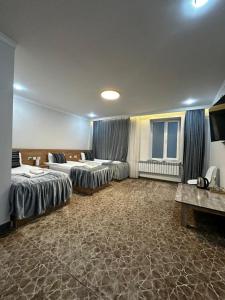 a hotel room with two beds and a television at Asmanguesthouse in Naryn