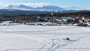 a snowy field with a town and mountains in the background at Morgondoppet - Olen Funäsdalen in Funäsdalen