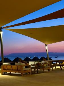 a group of people laying on beach chairs under an umbrella at Matarma Bay Hotel in Ras Sedr