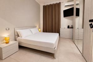 a white bedroom with a bed and a television at The Arco Rooms in Pomigliano dʼArco +7 photos