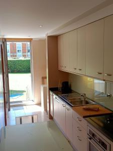 a kitchen with white cabinets and a large window at Pacos Beach House in Lavra