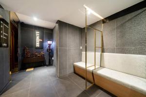 a bathroom with a bench and a man in the background at Yeoksam Lumiere Hotel in Seoul