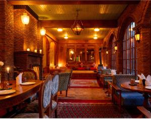 a restaurant with tables and chairs and a fireplace at Hazaar Dastaan Kashmir in Srinagar