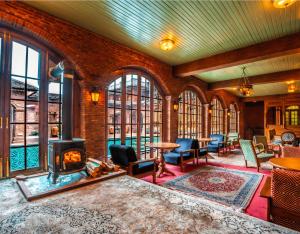 a living room with a fireplace and chairs and windows at Hazaar Dastaan Kashmir in Srinagar