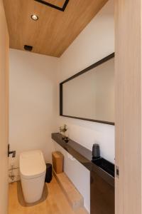 a bathroom with a toilet and a large mirror at Kuro Hakuba in Hakuba