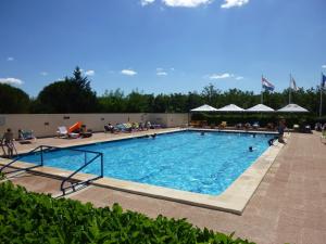a large swimming pool with people sitting around it at Les 4 mousquetaires in Méjannes-le-Clap