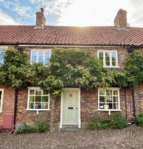 a brick house with a white door and windows at The Durham Ox in Crayke