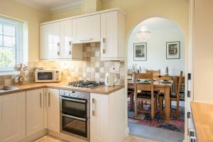 a kitchen with white cabinets and a dining room at Boyd’s Bungalow, Lowestoft in Lowestoft