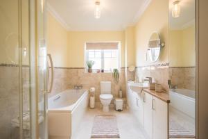 a bathroom with a tub and a toilet and a sink at Boyd’s Bungalow, Lowestoft in Lowestoft +17 photos