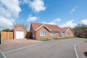 a red brick house with a white garage at Boyd’s Bungalow, Lowestoft in Lowestoft