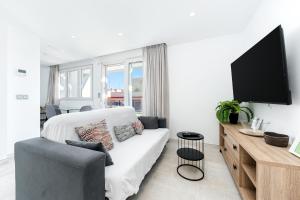 a living room with a white couch and a flat screen tv at Sunrise Center Suites in Torrevieja +42 photos