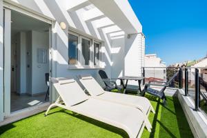 a balcony with white chairs and grass at Sunrise Center Suites in Torrevieja