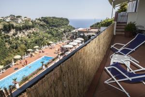 a balcony with chairs and a swimming pool with people at The Loft Via Torricella in Ravello