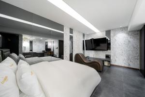 a bedroom with a white bed and a flat screen tv at Yeoksam Lumiere Hotel in Seoul