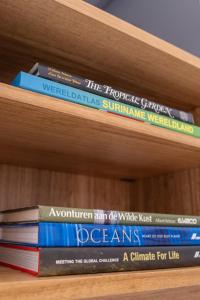 a stack of books sitting on a book shelf at Bantaskine Apartments in Paramaribo