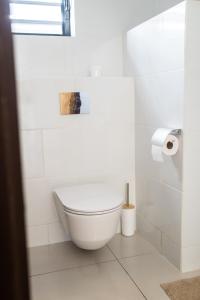 a white bathroom with a toilet and a roll of toilet paper at Bantaskine Apartments in Paramaribo