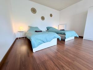 two beds in a white room with wood floors at Über den Dächern von Borghorst - direktes Zentrum in Steinfurt +16 photos