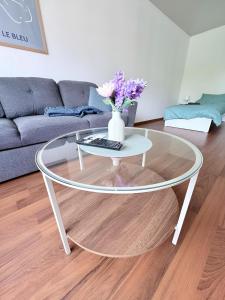 a glass coffee table with a vase with flowers on it at Über den Dächern von Borghorst - direktes Zentrum in Steinfurt