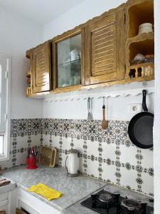 a kitchen with wooden cabinets and tiles on the wall at La maison douce Bizerte in Bizerte +1 photo