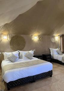 a bedroom with two beds with white sheets at Sahara Luxe Camp in Merzouga