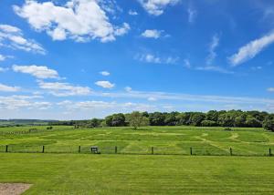 a green field with a fence and a blue sky at Hampshire Hills in Bighton